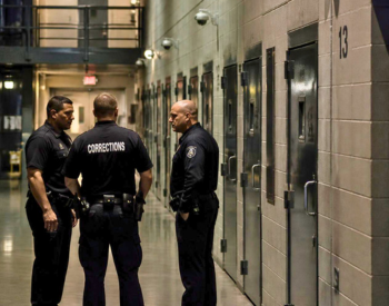 Three corrections officers conferring in the hallway of a corrections facility