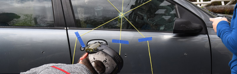 Students measure bullet holes in the side of a car in a criminal investigation exercise